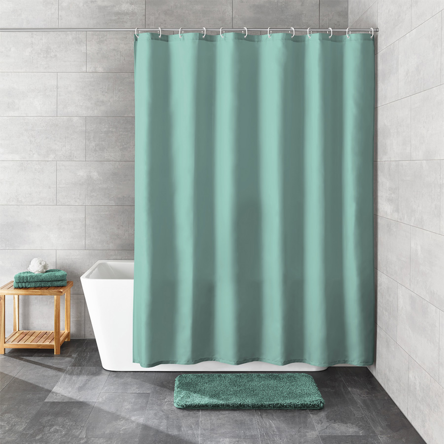 Badezimmer mit freistehender Wanne, gr&uuml;nem Duschvorhang, passendem Badteppich und Handt&uuml;chern